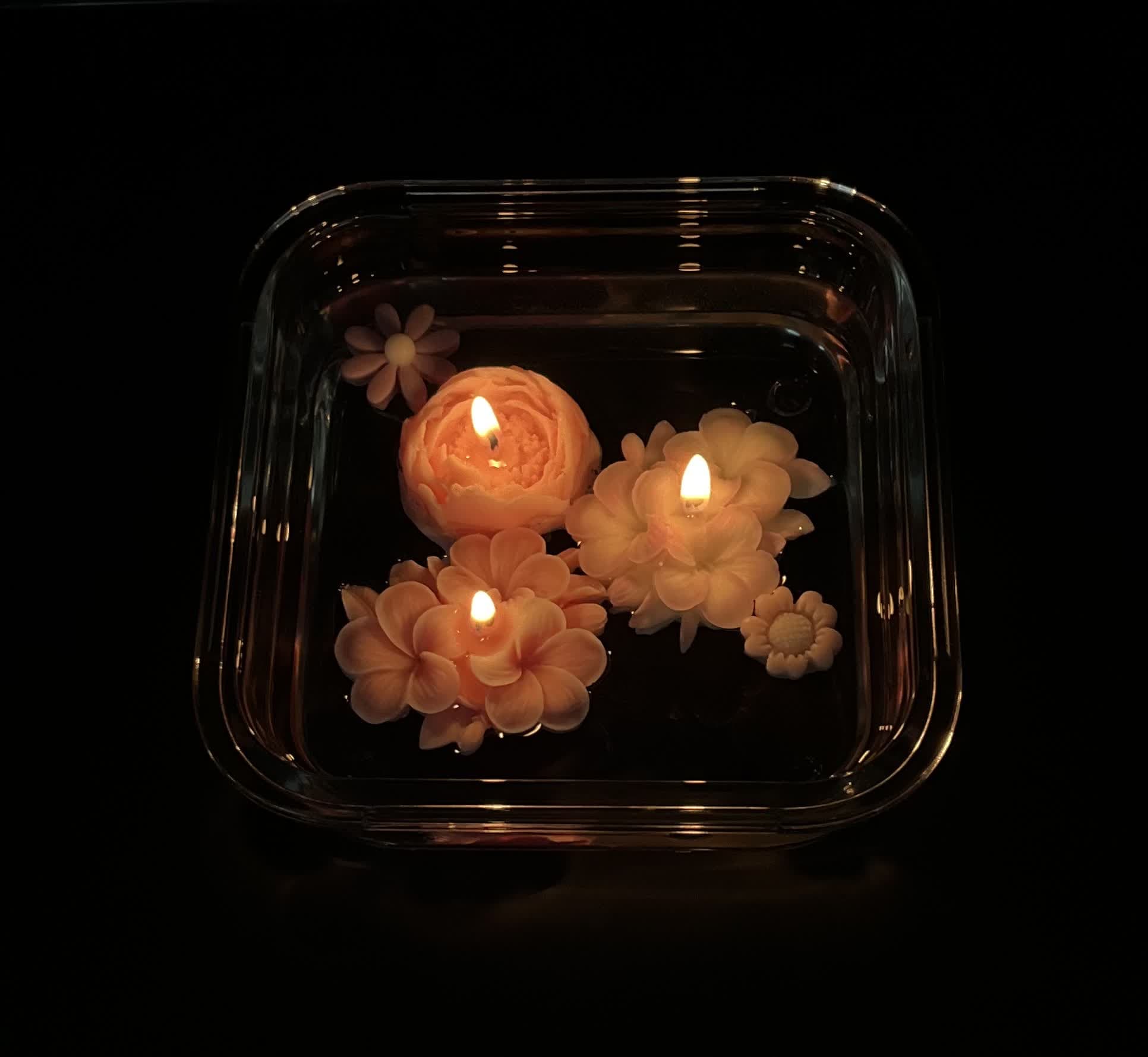 A customer’s lit flower candles floating in a tray