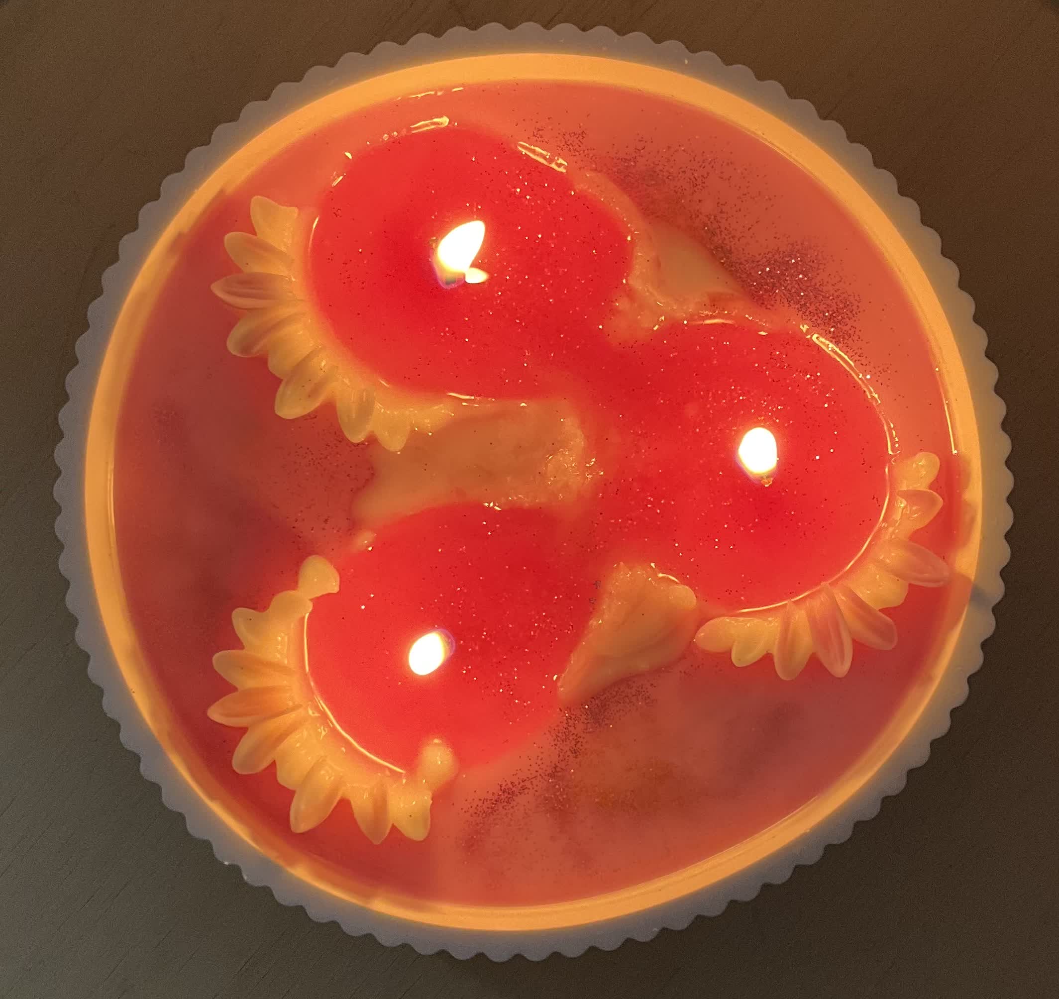 A customer’s lit red candle with flower details, from above